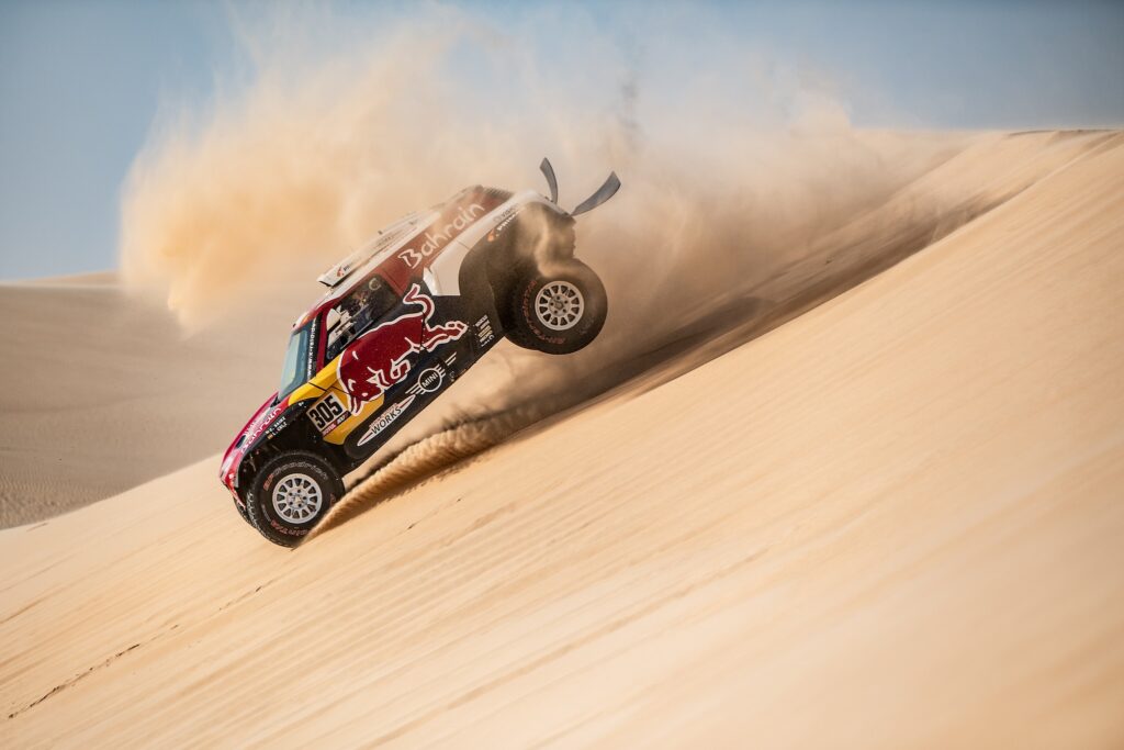 First-placed for the auto category JCW X-RAID Team Spain's driver Carlos Sainz (C), celebrates as he is congratulated by second-placed Toyota's team Qatar's driver Nasser Al-Attiyah (R) and by third-placed JCW X-RAID Team France's Stephane Peterhansel on the finish area in Qiddiya at the end of the stage 12 of the Dakar 2020 between Haradh and Qiddiya, Saudi Arabia, on January 17, 2020.